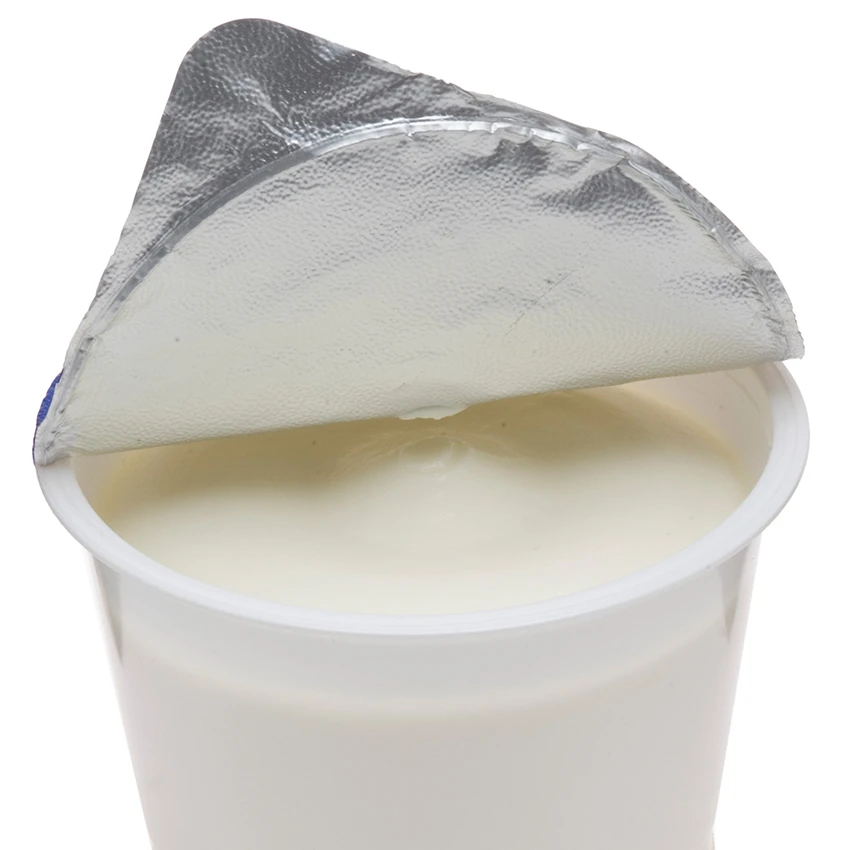 ein weißer Joghurtbecher mit hochgeklapptem Deckel