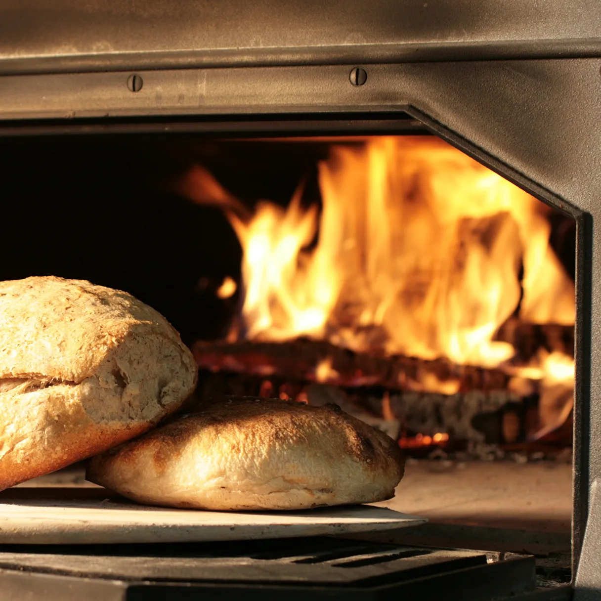 Brot vor Ofen mit Flammen im Hintergrund
