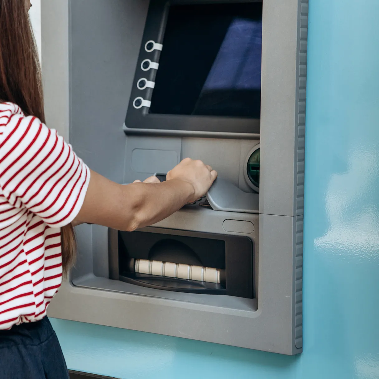 Frau hebt Geld an einem Geldautomaten ab.